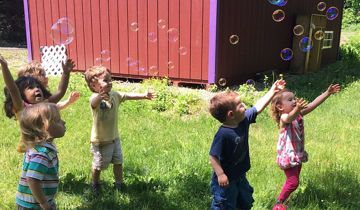 Kids playing with bubbles near the barn.