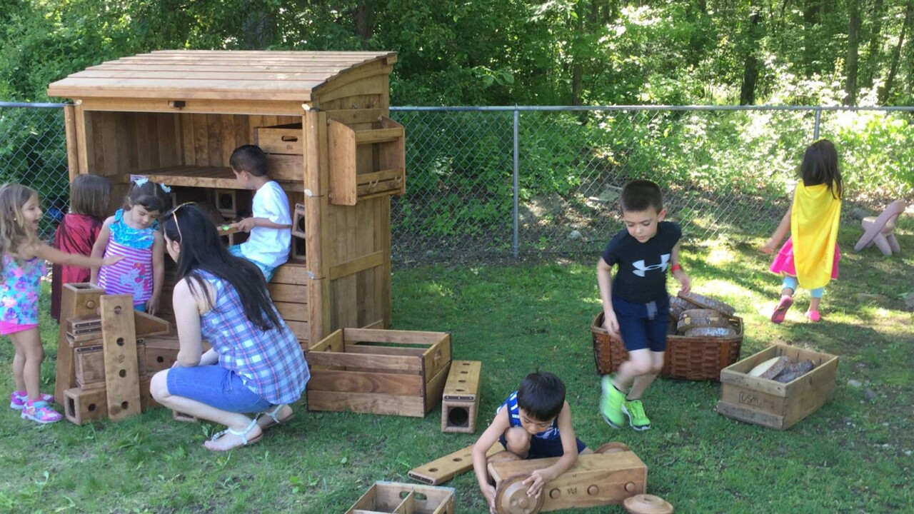 Kids outside building a car out of wood blocks.