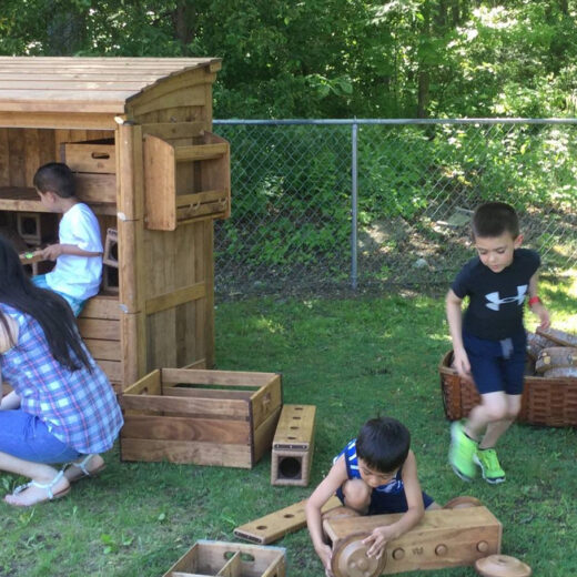 Kids outside building a car out of wood blocks.